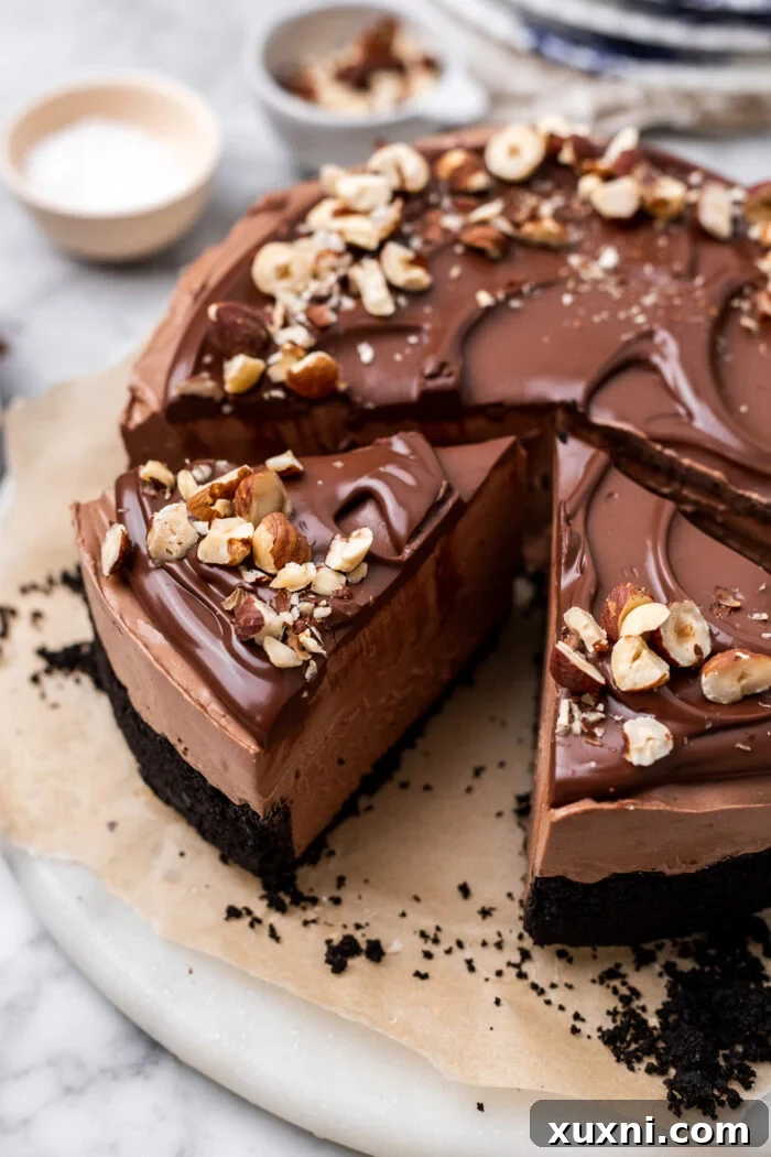 A second view of the sliced vegan Nutella cheesecake on a plate, highlighting its smooth filling and generous chocolate ganache topping.