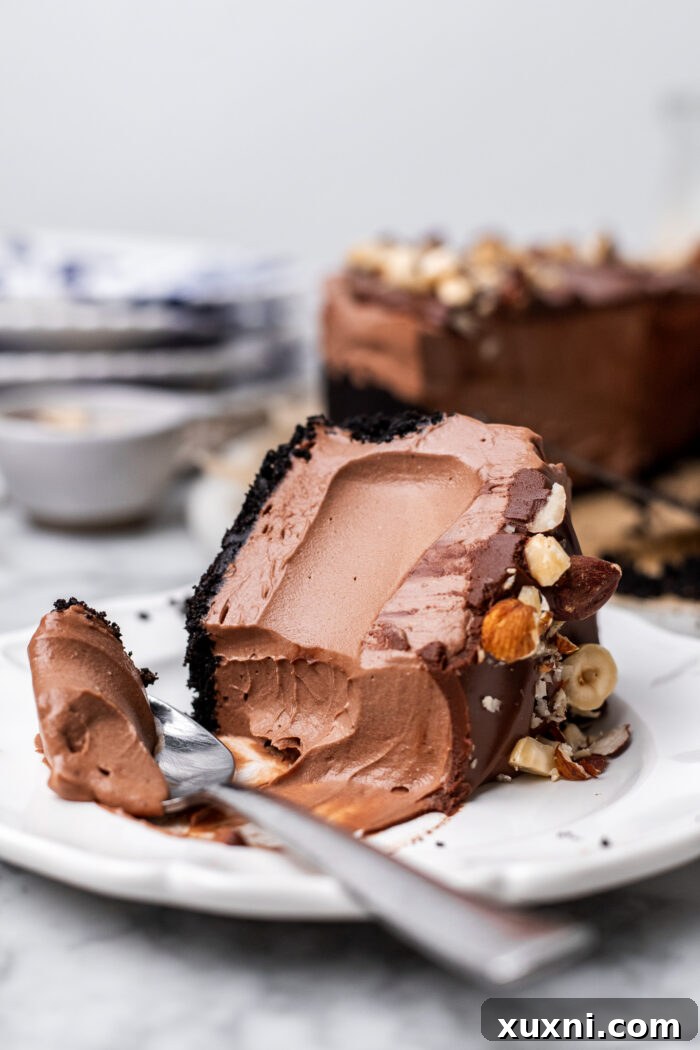 A close-up of a slice of vegan Nutella cheesecake with a bite taken out, showcasing the smooth, creamy filling and crunchy Oreo crust.