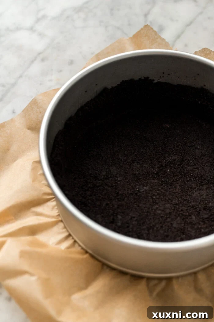 Oreo cookie crust pressed into a springform pan, ready for chilling.