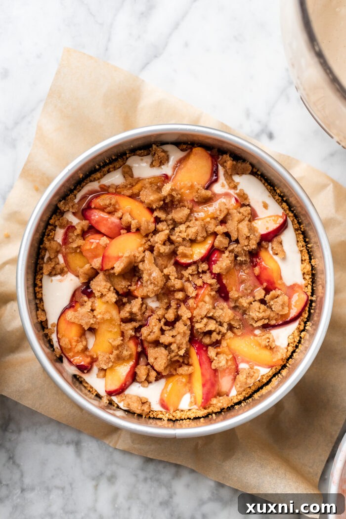 Roasted peaches and crumble topping added over the first cheesecake batter layer.