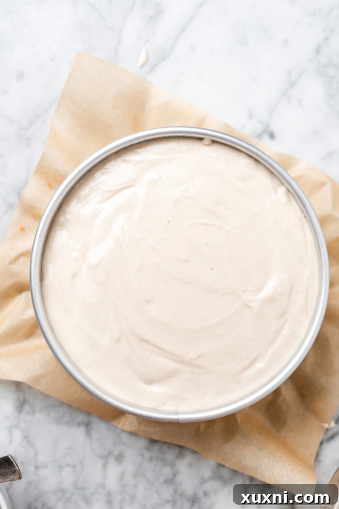 The remaining cheesecake batter poured over the peach and crumble layers, smoothing the top.