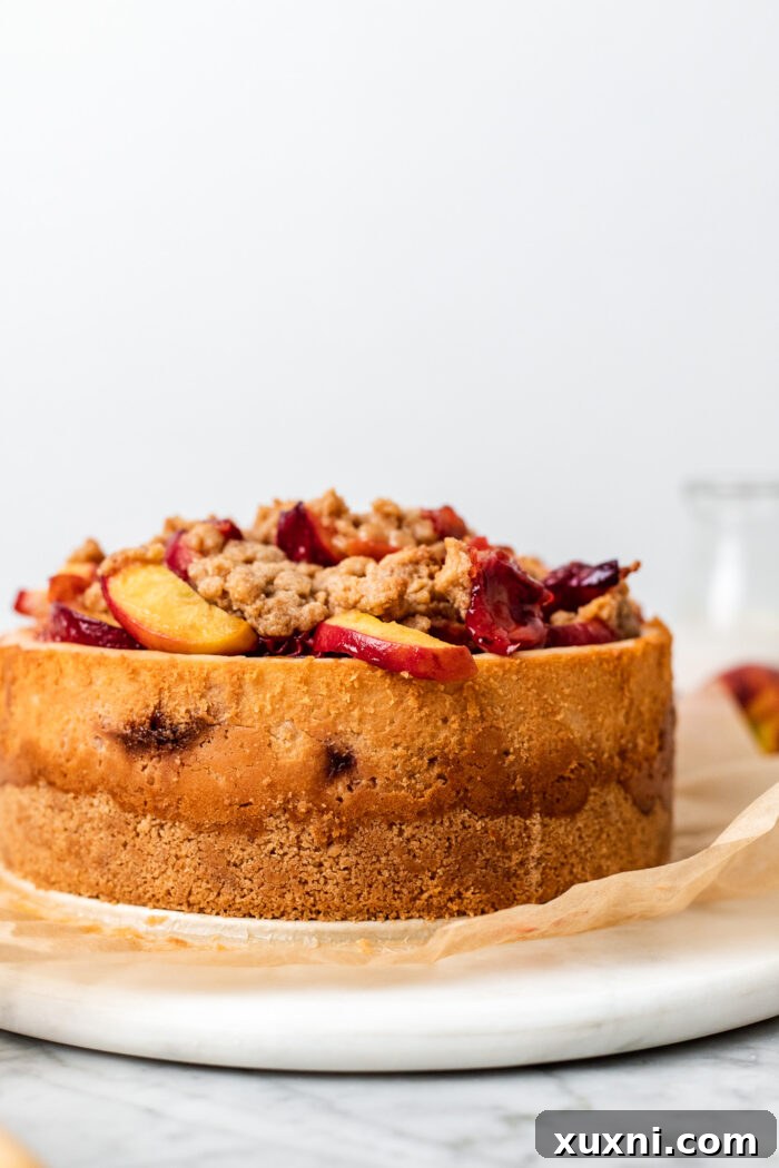 Beautifully topped vegan peach cobbler cheesecake, adorned with freshly roasted peaches and crumble.