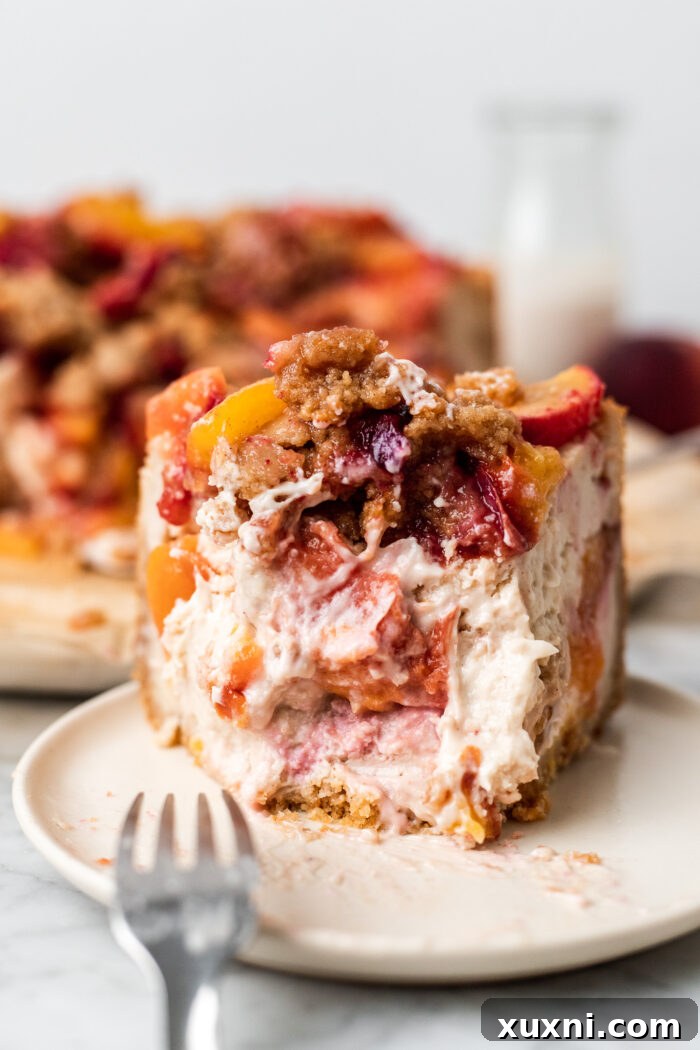 A delicious bite taken from a slice of vegan peach cobbler cheesecake, revealing the creamy interior.