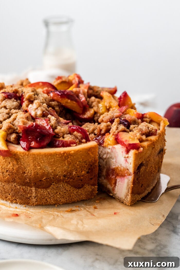 Close-up of a perfectly baked and sliced vegan peach cobbler cheesecake, showing the intricate layers and smooth texture.