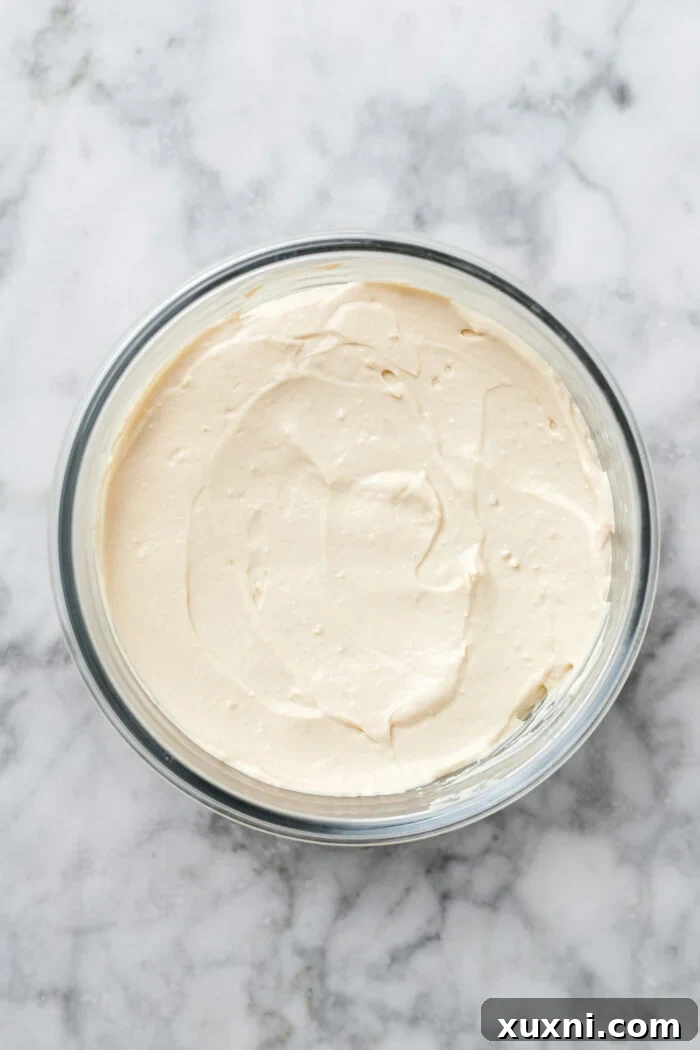 A container filled with freshly made, smooth vegan cream cheese, ready to be chilled and set.