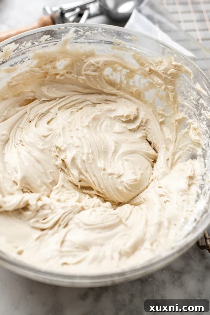 Fluffy vegan cream cheese frosting swirled on top of a delicious cupcake, showcasing its smooth and spreadable texture.