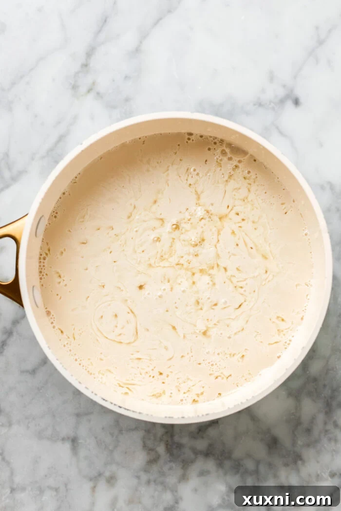 Pea milk curdling in a saucepan after lemon juice has been added and brought to a boil.