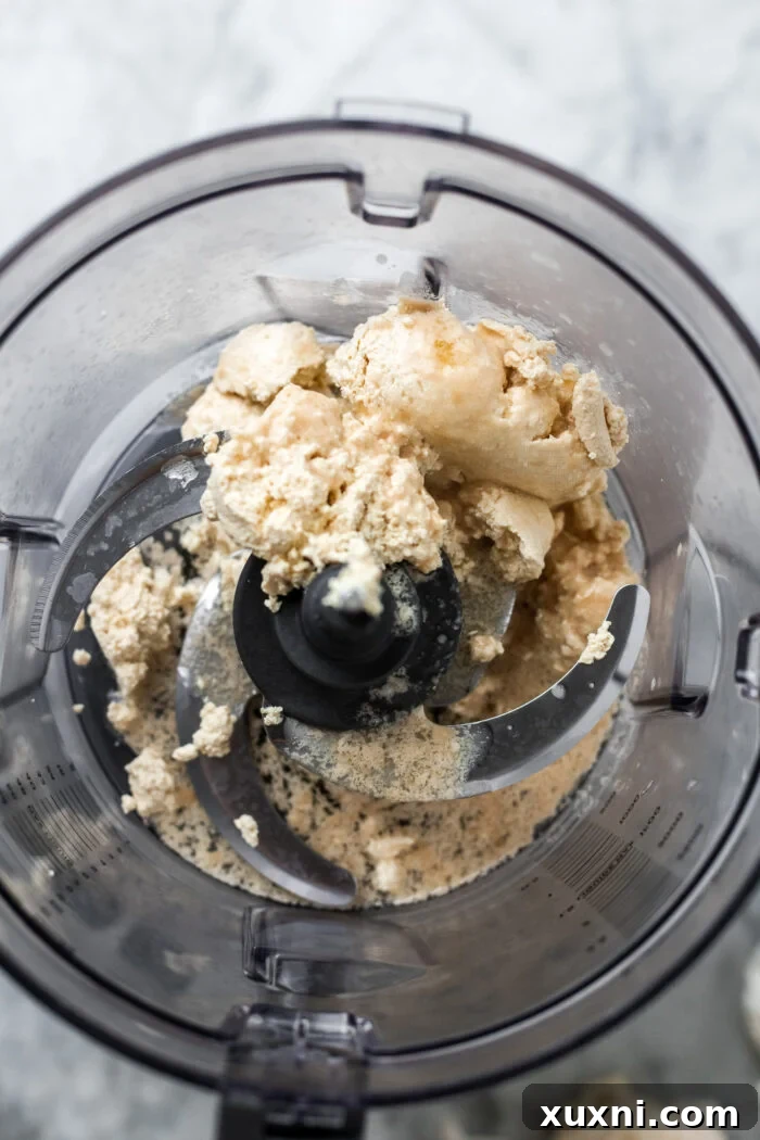 Pea milk curds, vegan butter, and extra lemon juice placed in a food processor, ready for blending into smooth cream cheese.