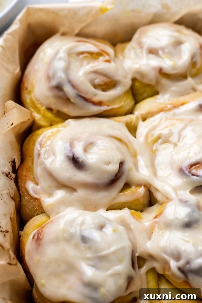 Small Batch Gooey Lemon Sweet Rolls Plant Based 15 A close-up of a single frosted vegan lemon sweet roll, showing the generous layer of cream cheese icing and the soft dough.