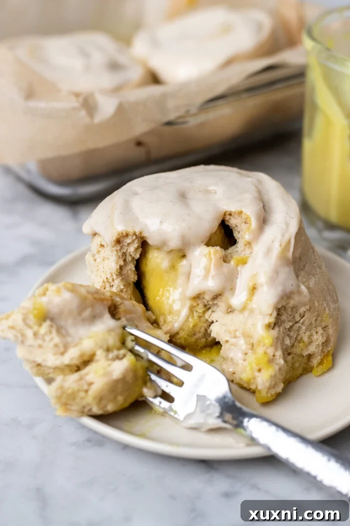 Small Batch Gooey Lemon Sweet Rolls Plant Based 17 A single gluten-free lemon sweet roll on a plate, generously frosted and ready to eat.