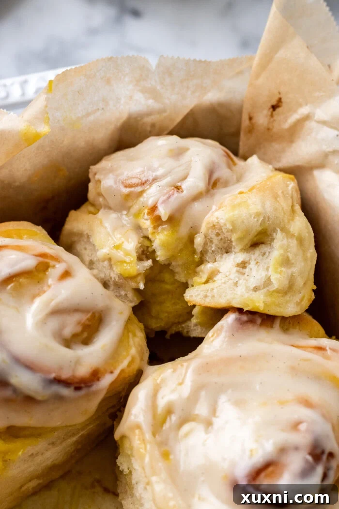 Small Batch Gooey Lemon Sweet Rolls Plant Based 3 A partially eaten vegan lemon sweet roll, showing the gooey lemon curd filling and fluffy dough inside a baking dish.