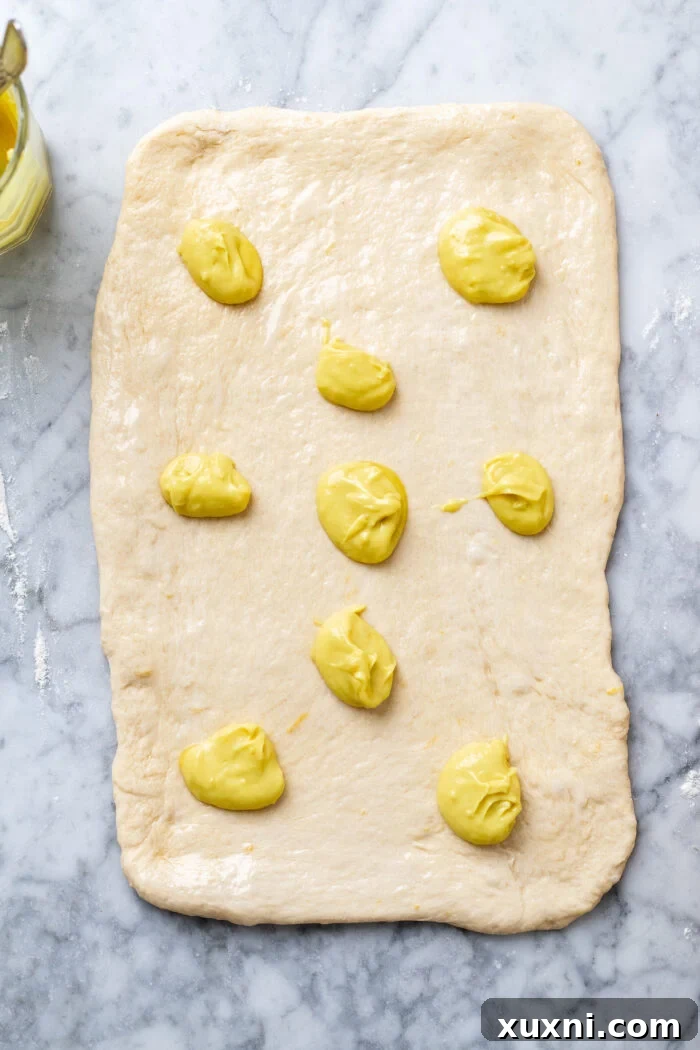 Small Batch Gooey Lemon Sweet Rolls Plant Based 9 A rectangle of rolled-out dough, brushed with melted vegan butter and dotted with spoonfuls of lemon curd.