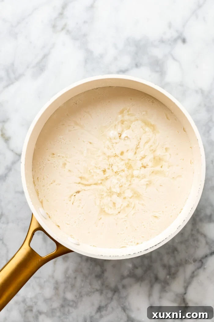 Pea milk and lemon juice gently heating in a saucepan, beginning to curdle.