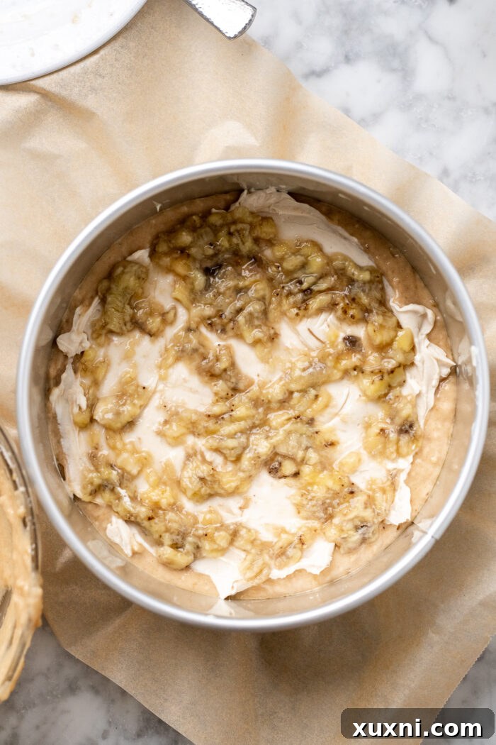 Layering the banana coffee cake with roasted bananas on top of the cream cheese, followed by the remaining batter.