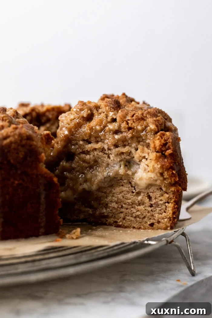 A perfectly sliced piece of vegan banana cream cheese coffee cake on a white plate.