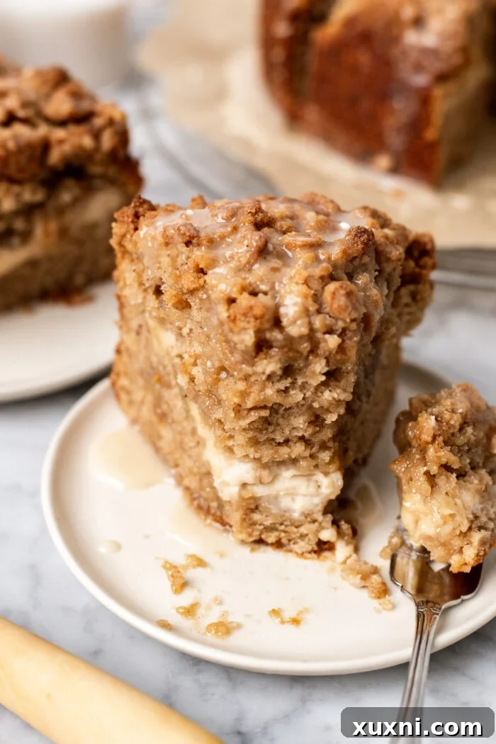 A close-up slice of cream cheese banana crumb cake on a plate, showing the creamy filling and cake texture.