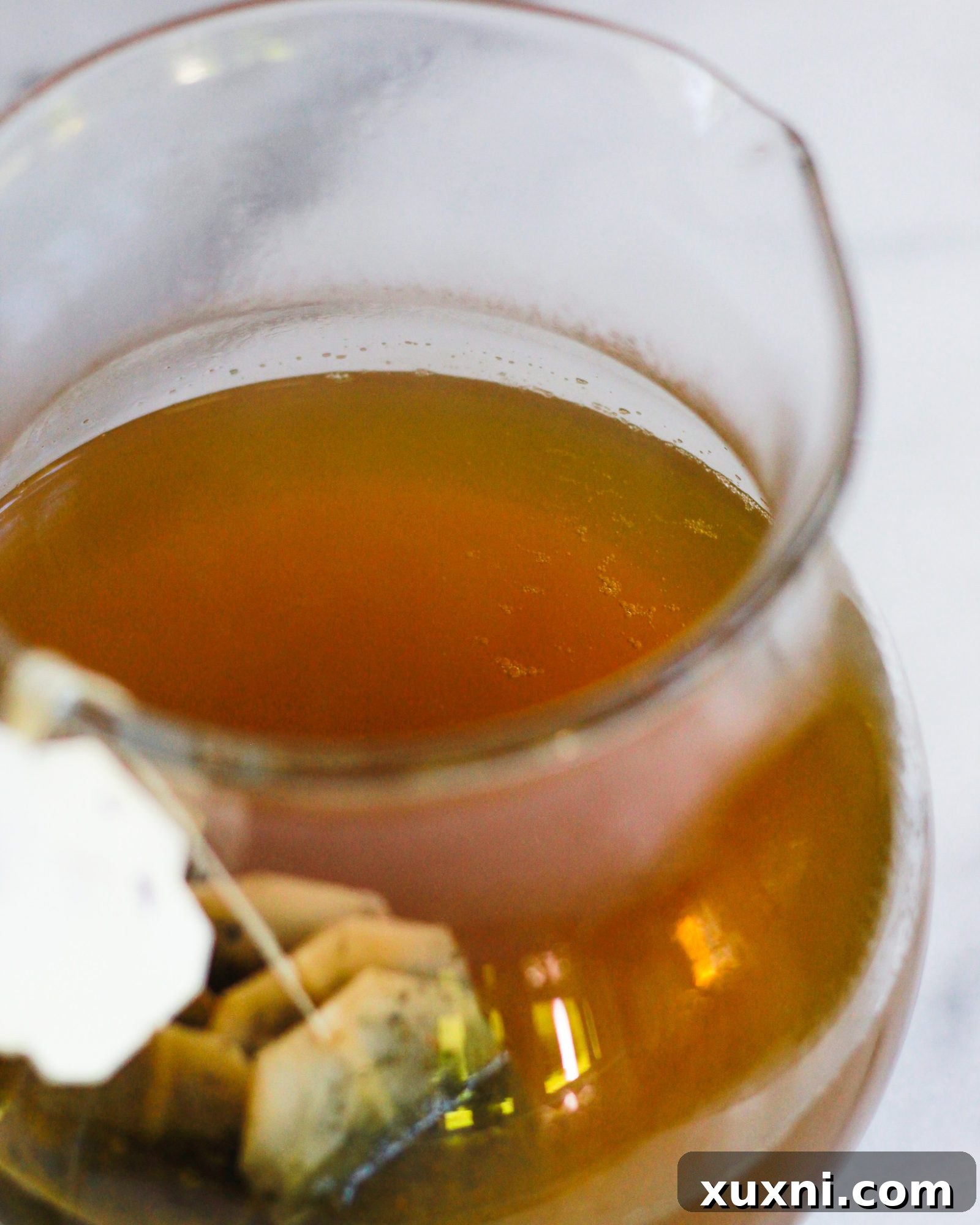 Clear pitcher filled with brewed iced green tea and ice, chilling