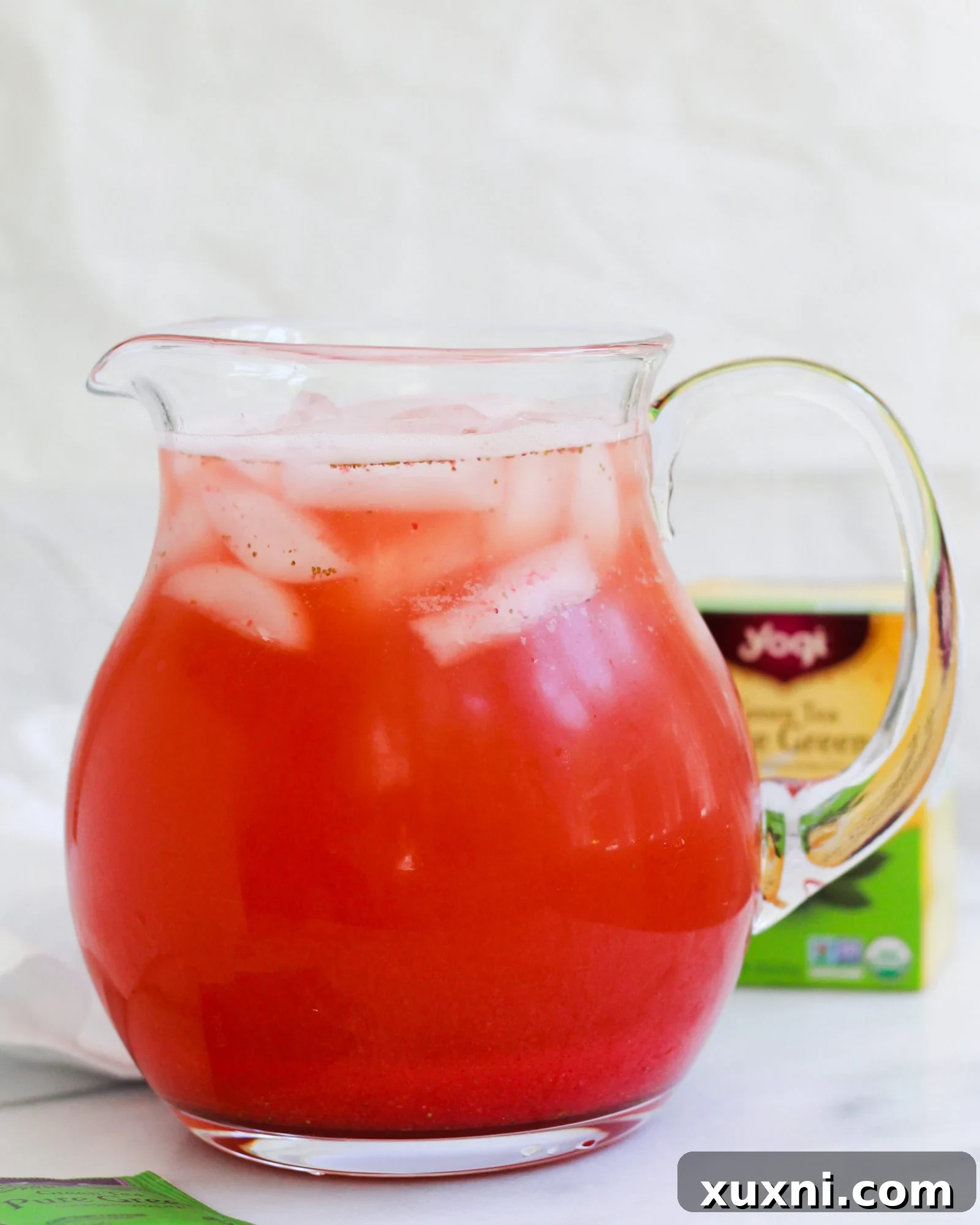 Large pitcher filled with mixed Iced Strawberry Green Tea Lemonade, ready to be served