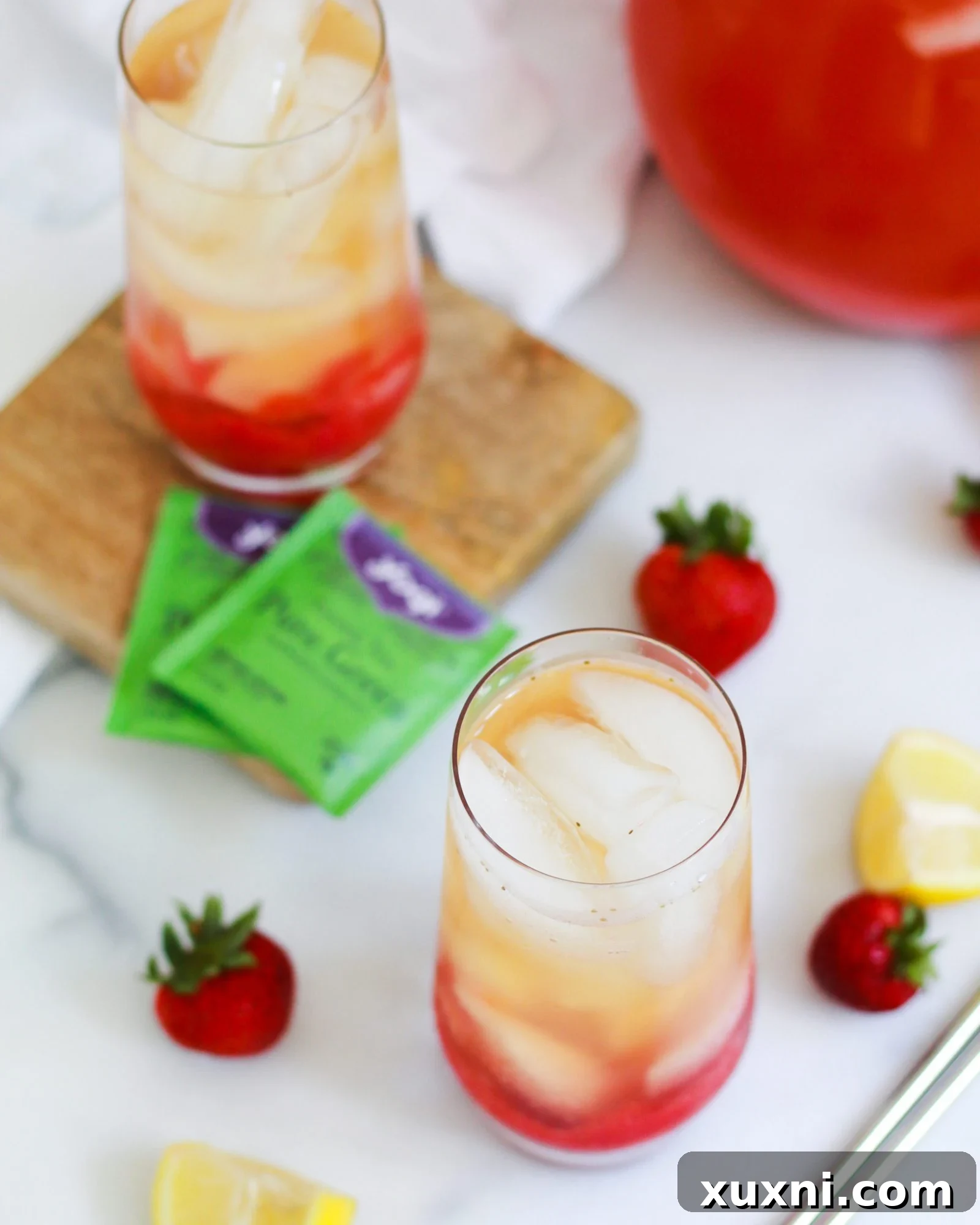Two glasses of Iced Strawberry Green Tea Lemonade, showcasing the vibrant colors and fresh garnishes