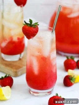 Mixed Iced Strawberry Green Tea Lemonade in a glass, with a single strawberry and lemon slice garnish