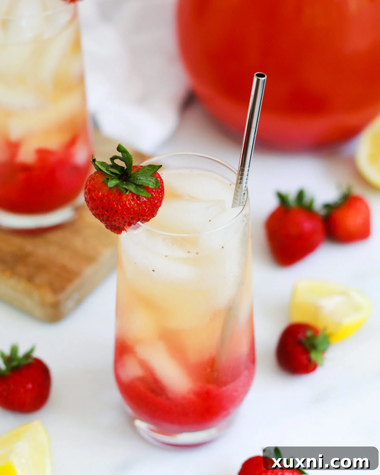 Single glass of iced strawberry green tea lemonade with a fresh strawberry garnish on the rim
