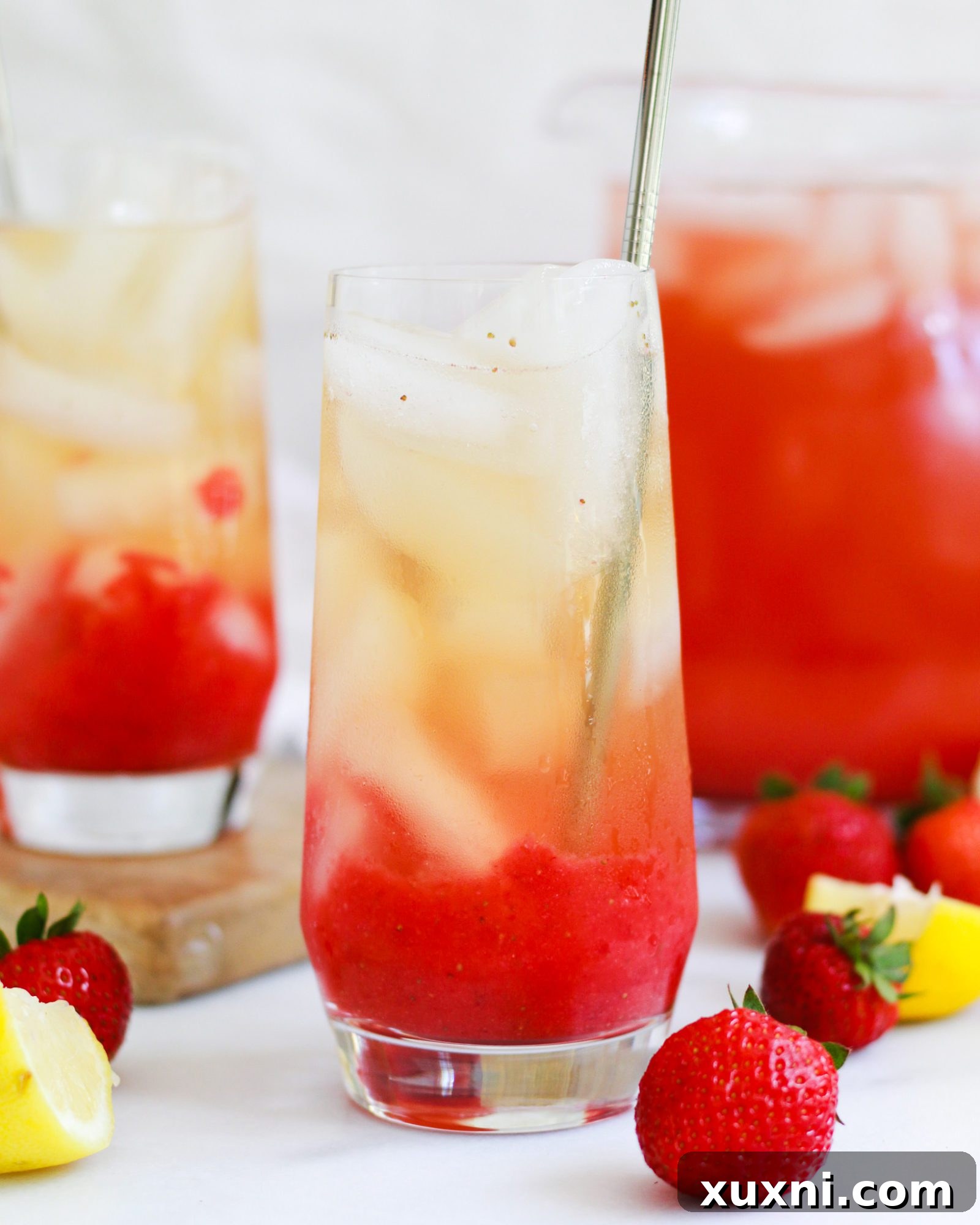Close-up of a glass of Iced Strawberry Green Tea Lemonade with a single strawberry and lemon slice garnish