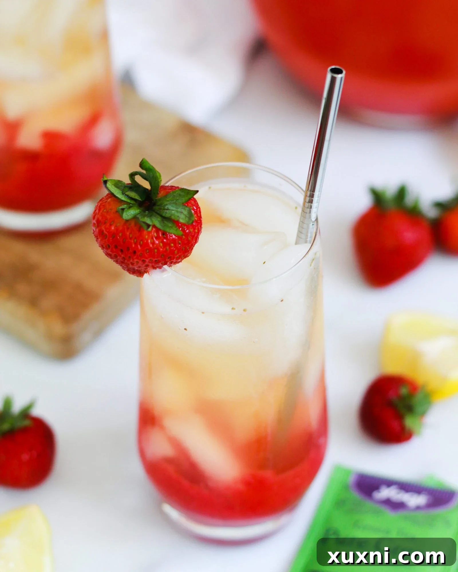 Close-up of Iced Strawberry Green Tea Lemonade in a glass, with a single strawberry on the rim for garnish