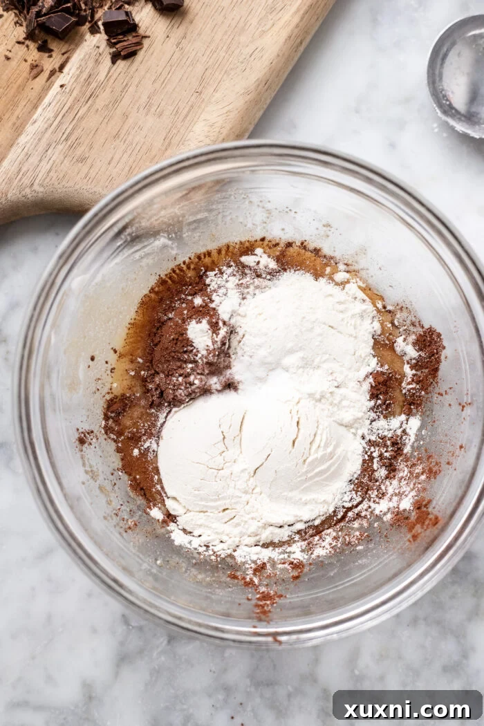 Beginning the cookie dough process by whisking together the wet ingredients: vegan butter, dairy-free yogurt, sugars, and vanilla extract.