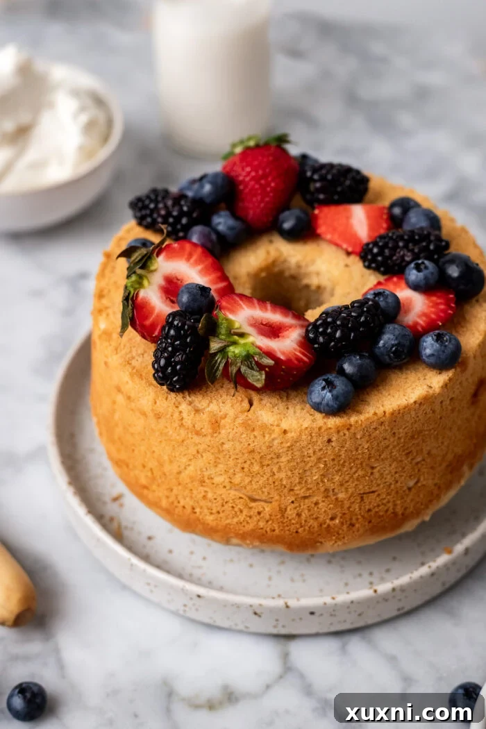 Heavenly Vegan Angel Food Cake 2 Delightfully light and fluffy vegan angel food cake on a plate, topped with dairy-free whipped cream and fresh berries, showcasing its perfect texture.