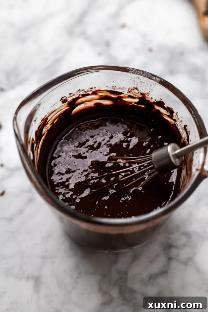Hot brown butter being poured over chocolate chips and cocoa powder to make fudge sauce