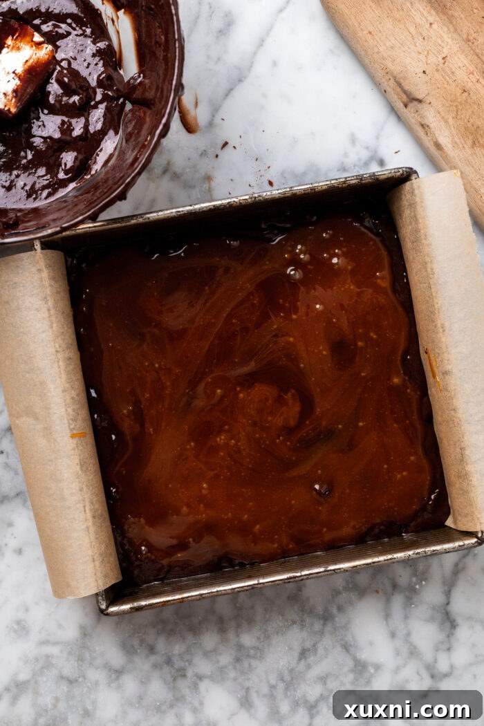 Assembling vegan salted caramel brownies with layers of batter and caramel