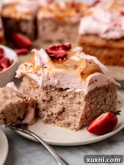 slice of strawberry sheet cake with a bite taken from it, showing the cake's fluffy interior