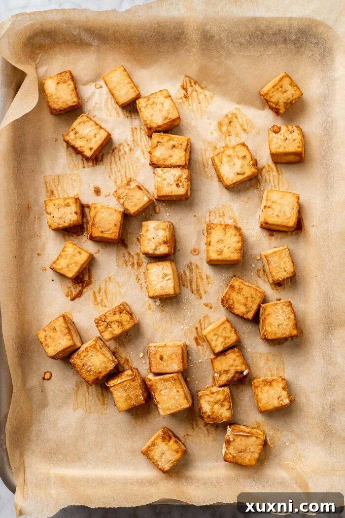 Golden-brown crispy baked tofu cubes arranged on a baking sheet, fresh out of the oven.