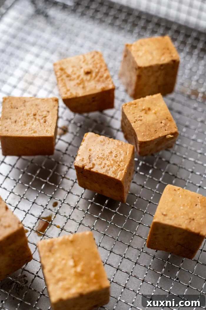 Starch-coated tofu cubes arranged in an air fryer basket, ready for cooking.