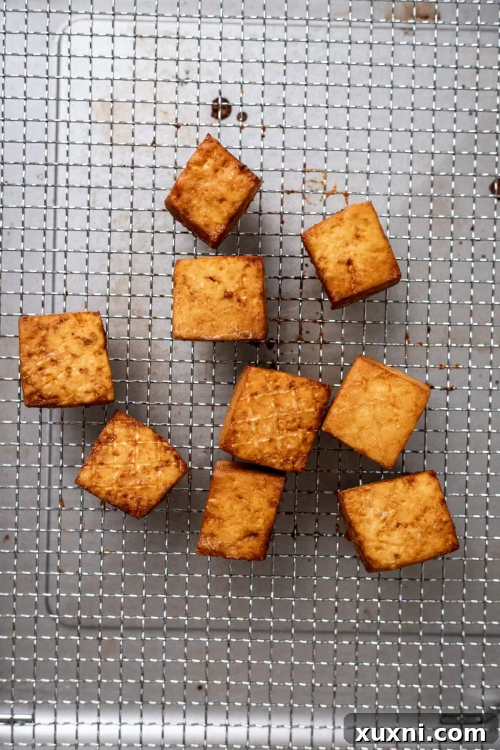Air fryer basket filled with golden, crispy tofu, illustrating the results of air frying.
