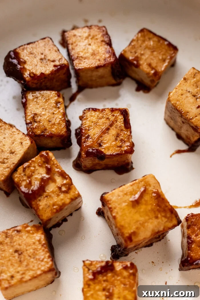 Close-up of crispy, pan-seared tofu in a skillet, showing off its golden and delicious texture.