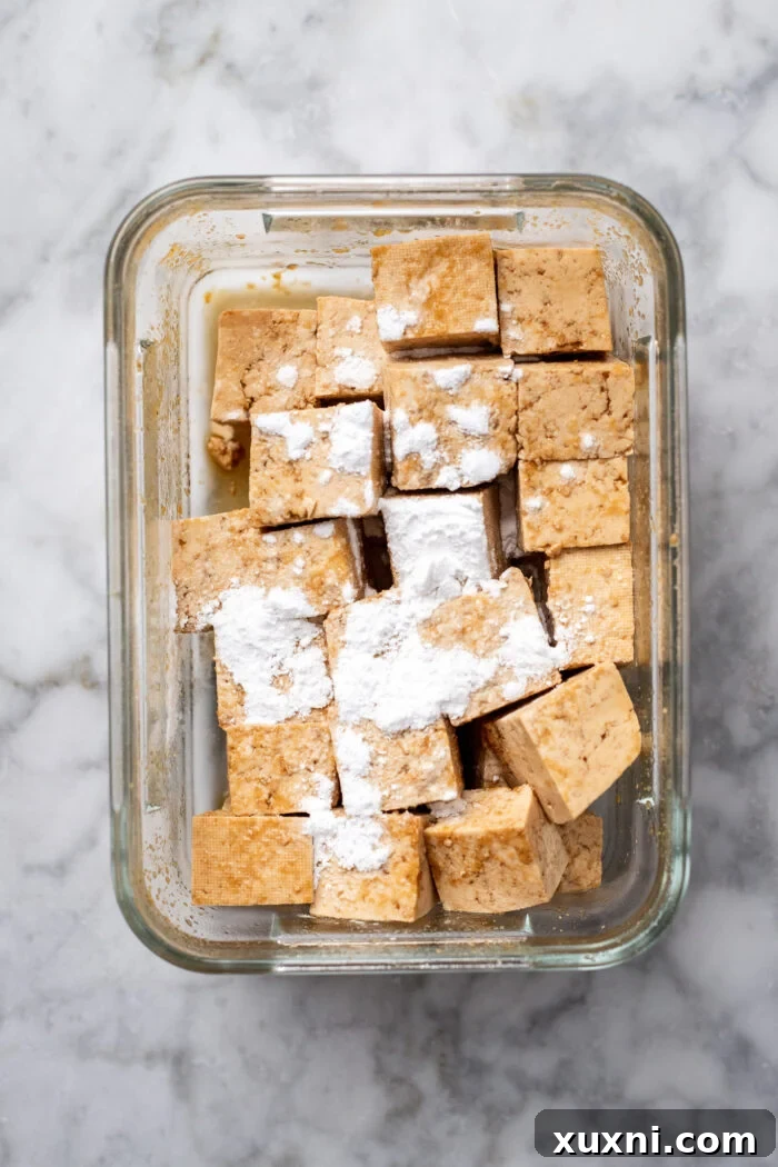 Cubed tofu lightly coated in white arrowroot starch, ready for cooking.