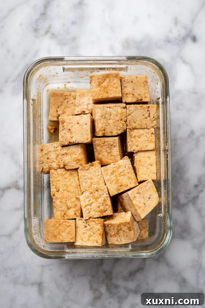 Marinated tofu, ready for cooking, showing the cubes fully coated in the savory liquid.