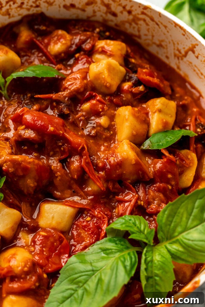 Cooked cherry tomato pasta in a rustic skillet, ready for serving.