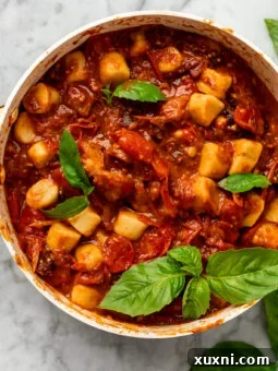 Fresh cherry tomato sauce in a pan with fluffy homemade gnocchi, garnished with basil.