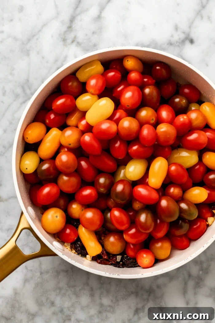 Whole fresh cherry tomatoes tossed in garlic and olive oil in a skillet before covering.