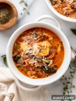 A vibrant, creamy vegan tortellini soup in a bowl, showcasing perfectly cooked tortellini, wilted kale, and a rich tomato base, ready to be enjoyed.