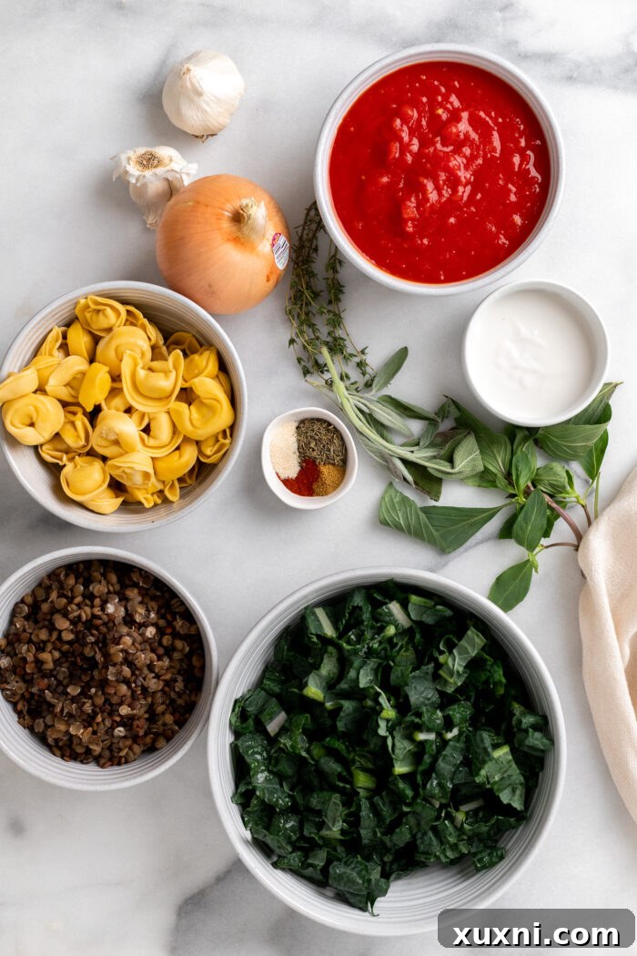 Various fresh ingredients for vegan tortellini soup laid out on a wooden cutting board, including fresh kale, onions, garlic, a jar of crushed tomatoes, and a package of vegan tortellini.