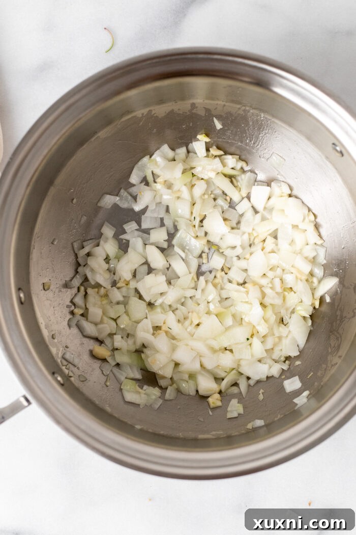 Diced onions and minced garlic gently sautéing in olive oil in a large pot, filling the kitchen with fragrant aromas as they soften to translucency.