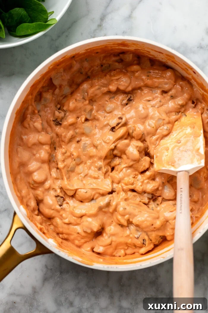 stirring in the butter beans to the creamy tomato sauce