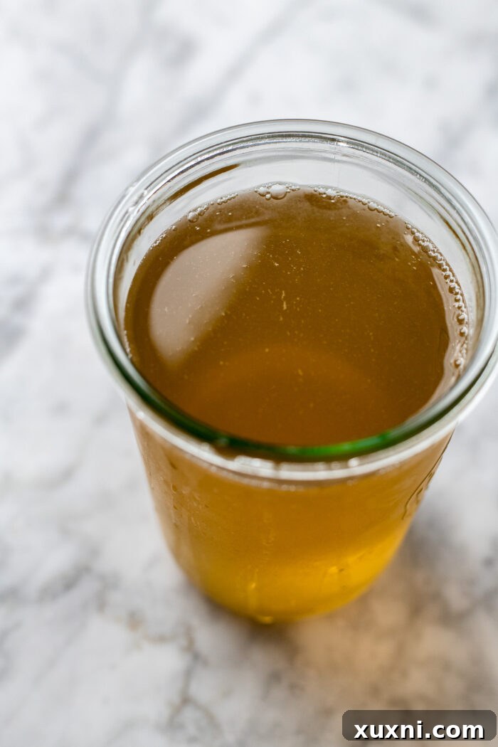 A glass jar filled with golden vegetable broth