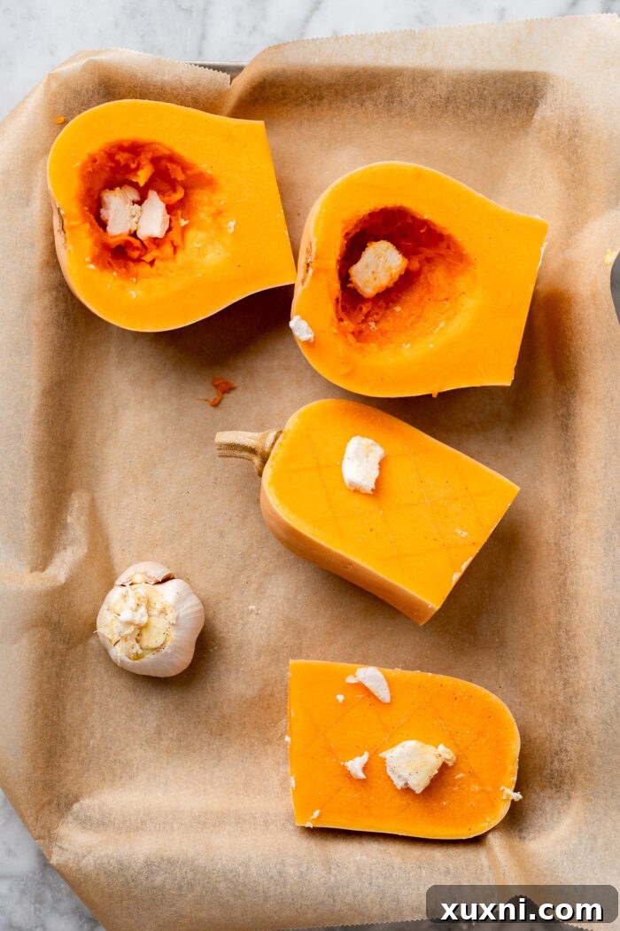 A whole garlic bulb with the top sliced off, ready to be drizzled with oil and roasted alongside butternut squash.