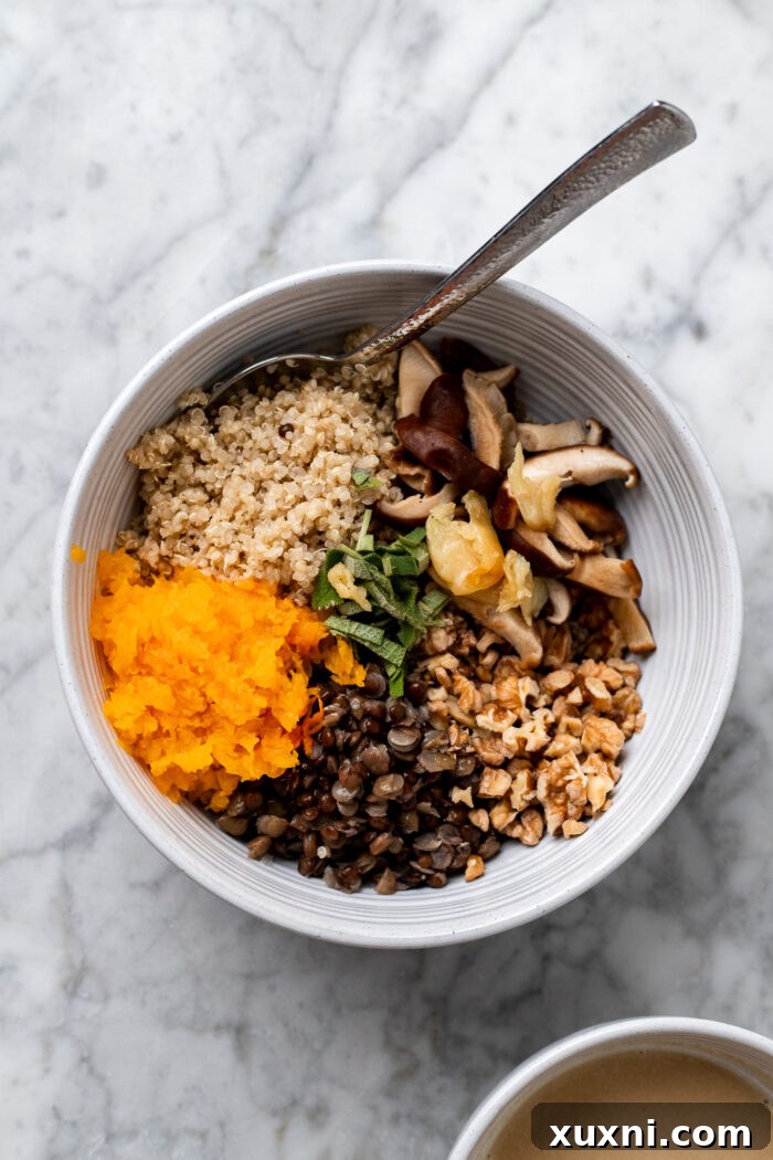 A large bowl containing the quinoa lentil stuffing mixture, with scooped butternut squash flesh and sauce, being mixed together.