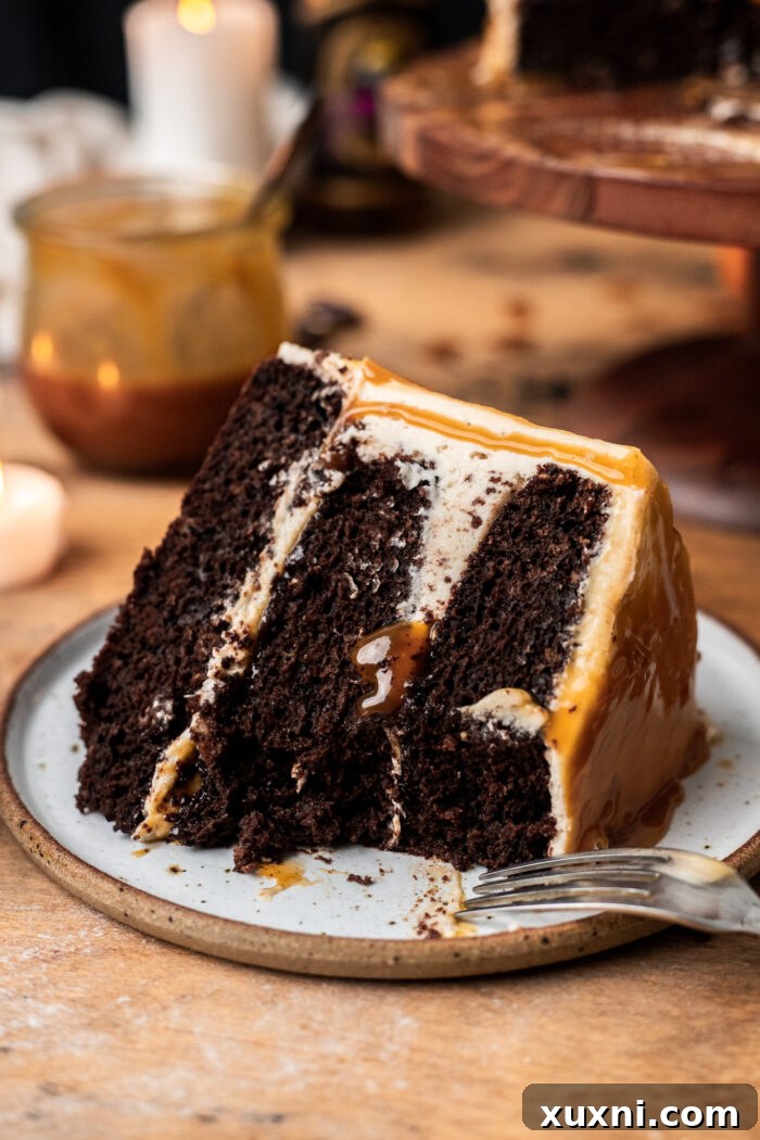 A slice of vegan chocolate butterbeer cake on a white plate, ready to be enjoyed.