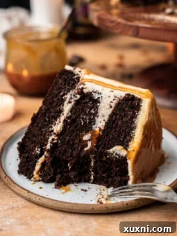Slice of vegan chocolate butterbeer cake on a plate, showing the rich layers and frosting.